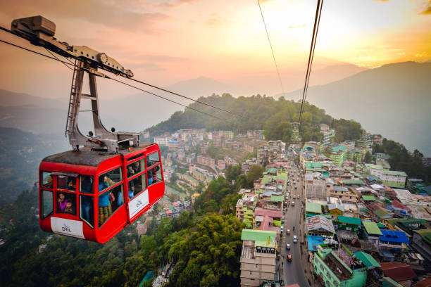 Gangtok,Sikkim - December 13 2017: Tourists enjoy a ropeway cable car/Gondola ride over Gangtok city during sunset. Amazing aerial cityscape of Sikkim. Foggy and golden hour. North east India tourism
